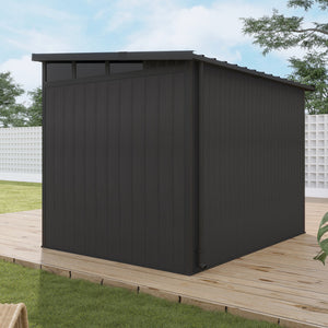 Black metal shed on a wooden deck with grass and trees in the background